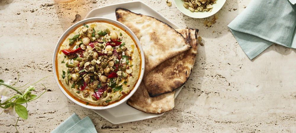 A hummus bowl topped with Struesli's organic granola, paired with bread.