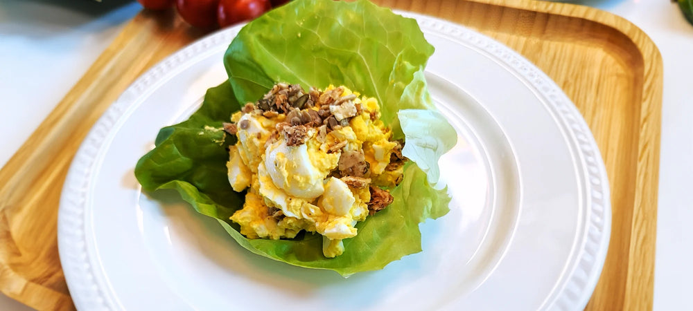 A salad wrap holding rich egg salad topped with Struesli granola.