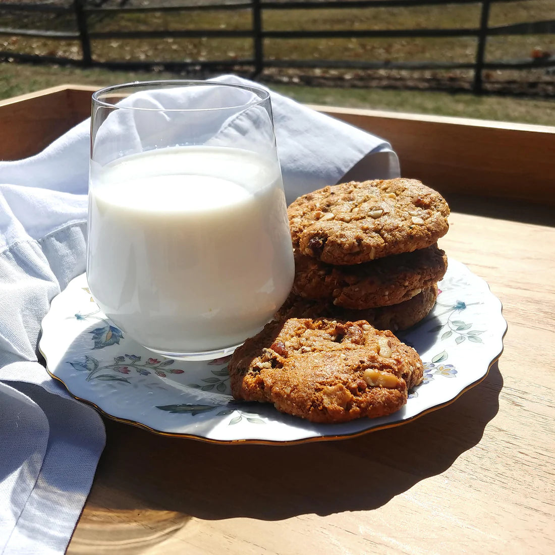 A plate of stacked Struesli and raisin cookies paired with a glas of milk.