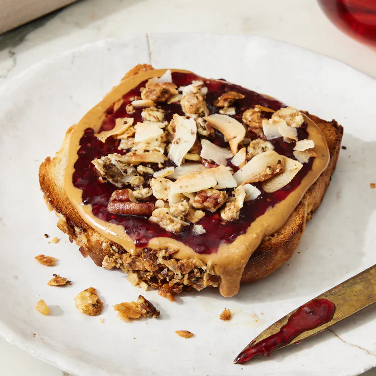 A nut-butter toast topped with jam and Struesli's organic granola.