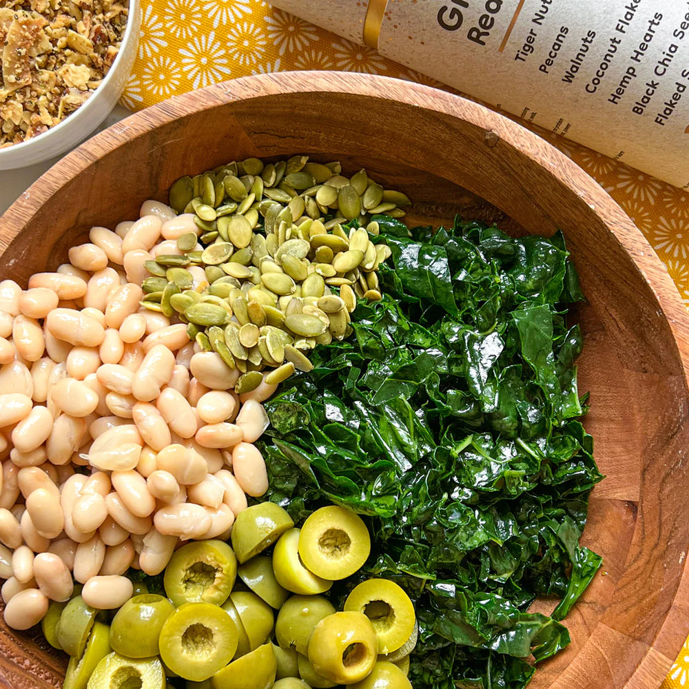 A wooden bowl of plant-based savory kale salad made using Struesli's organic granola.