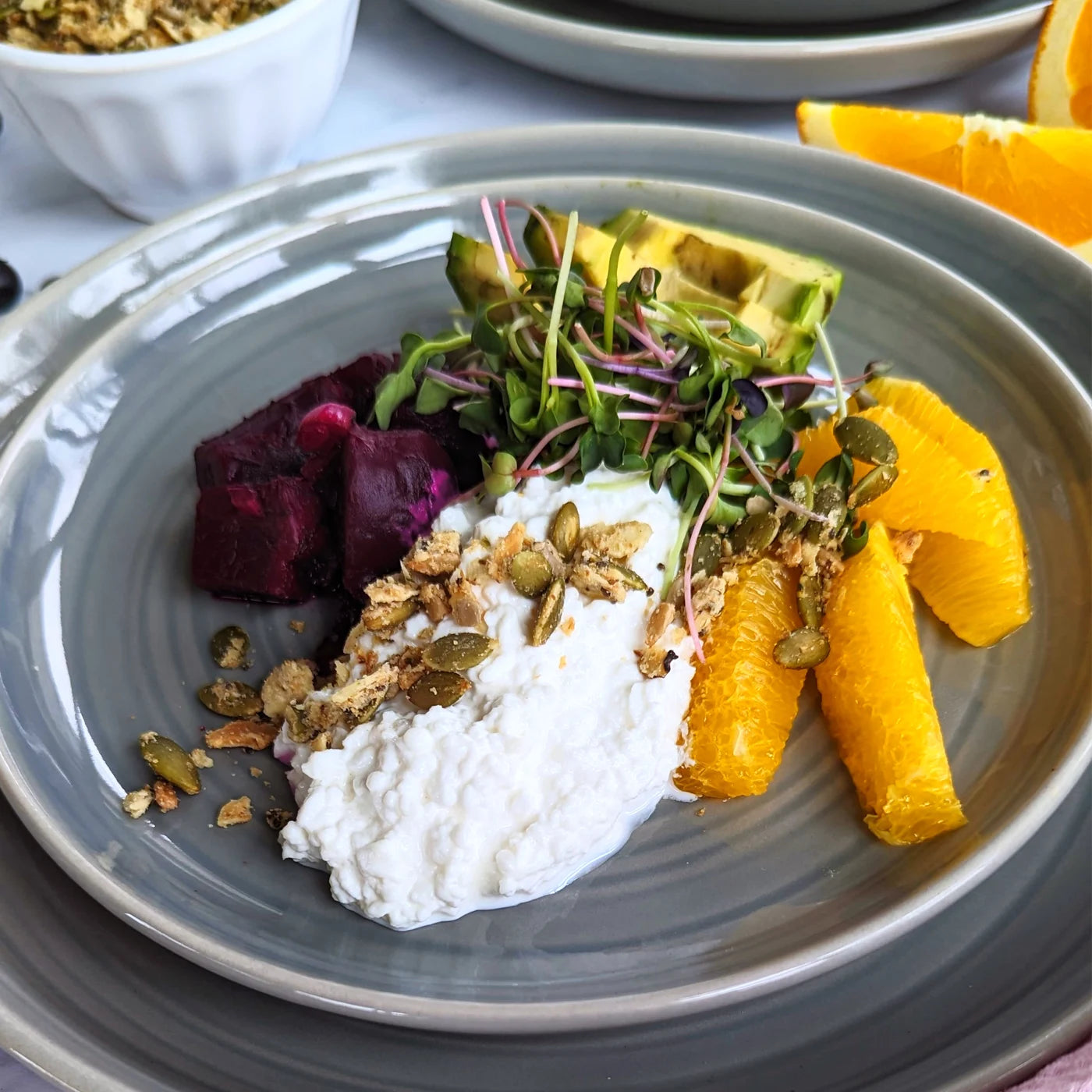 A plate of cottage cheese topped with micro greens, fruit and Struesli's organic granola.
