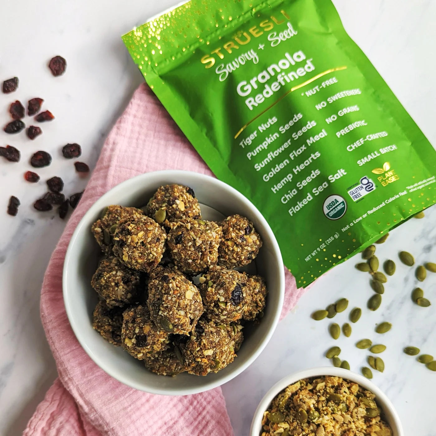 Nut-free bliss bites stacked in a bowl next to a bag of Struesli savory + seed granola.