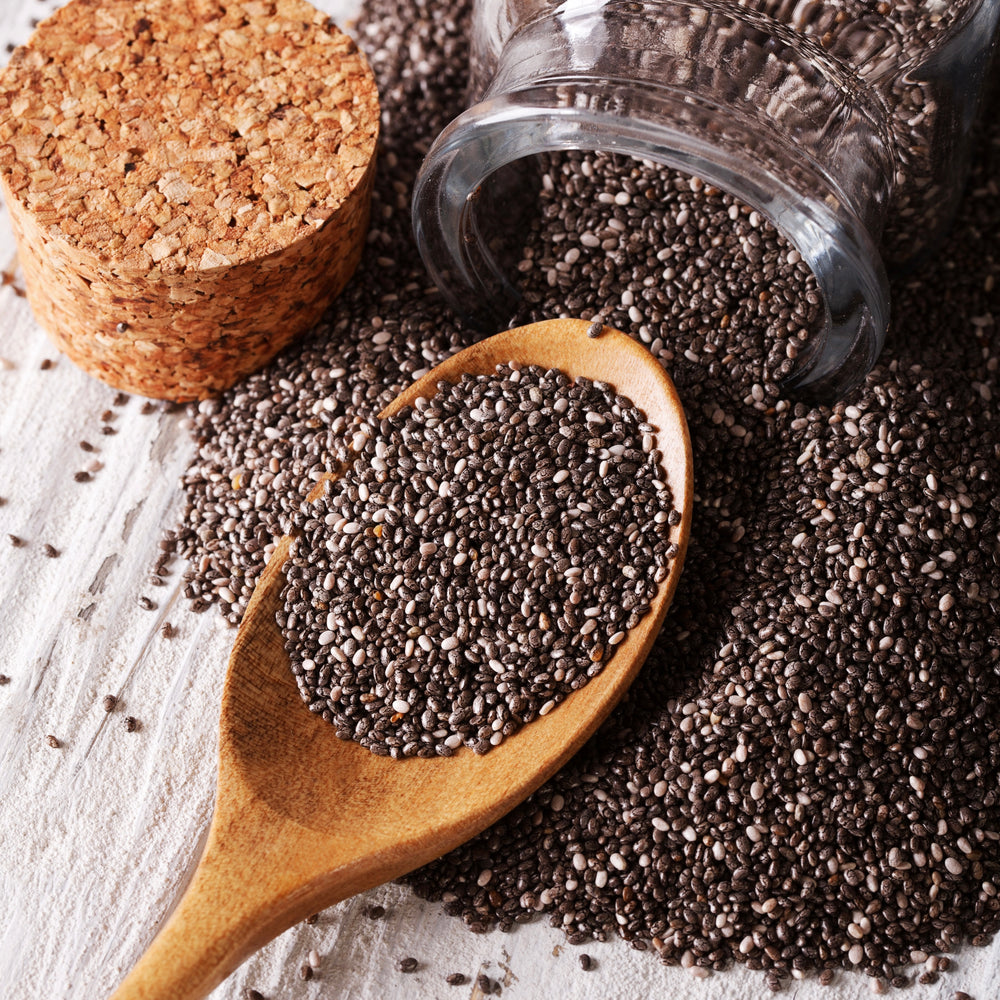 Chia seeds spilled from a jar and onto a wooden spoon