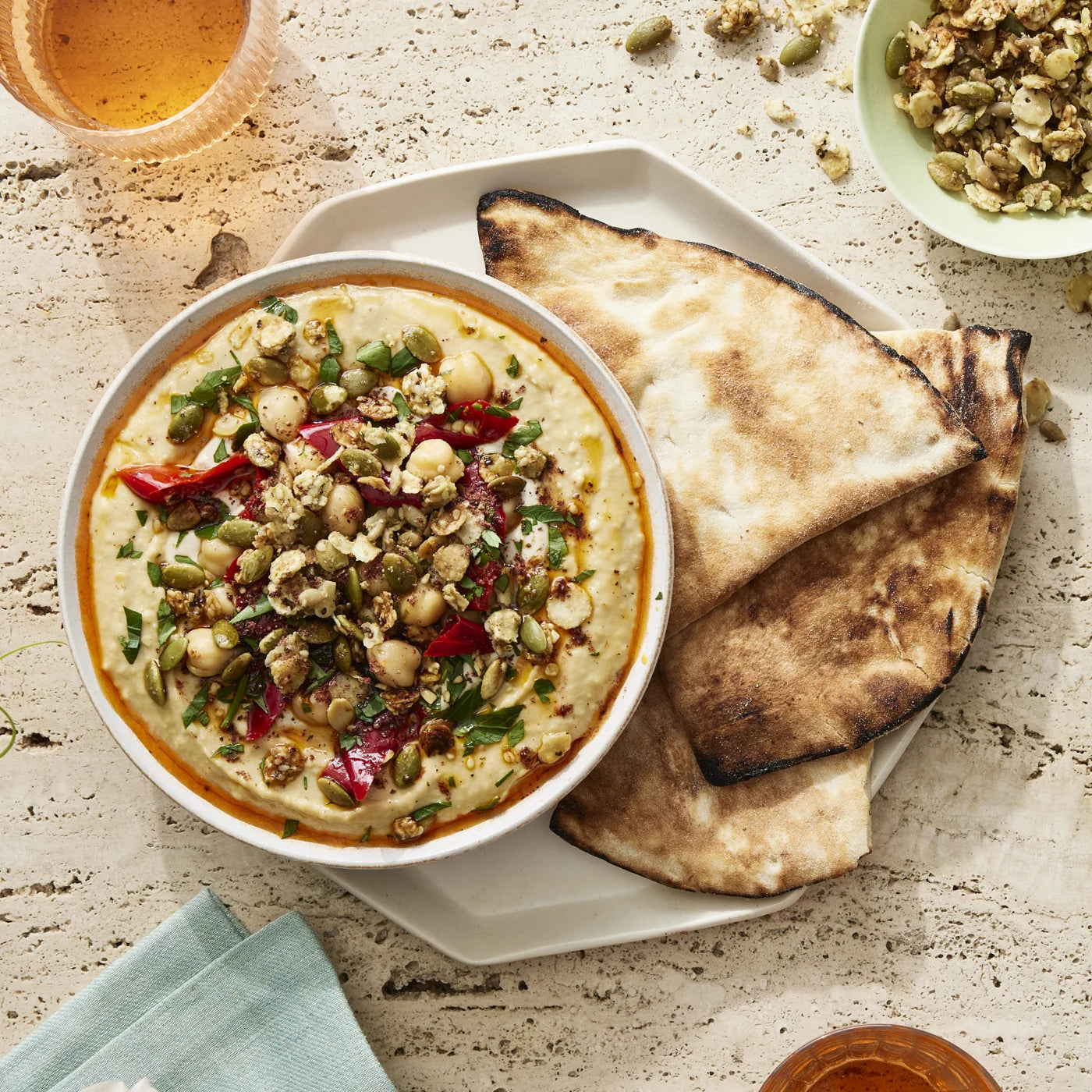 A bowl of hummus topped with Struesli granola, paired with a delicious flat bread.