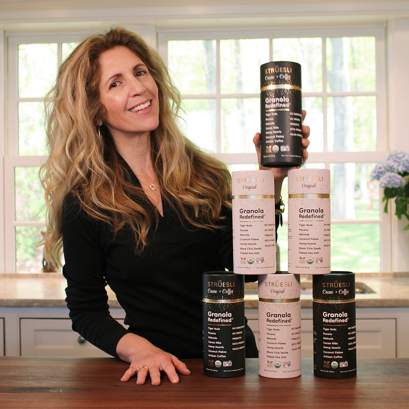 Adrienne Lufkin with several containers of Struesli granola stacked in a pyramid