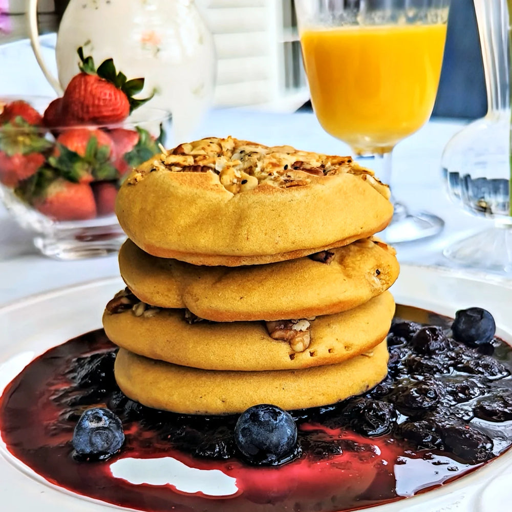 A golden stack of gluten-free superfood pancakes on top of blueberry compote.