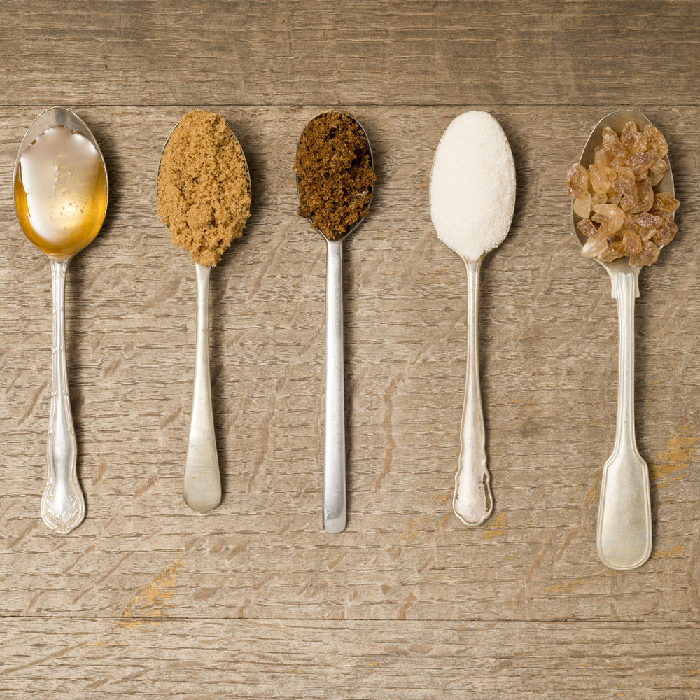 A row of spoons with various types of sugars