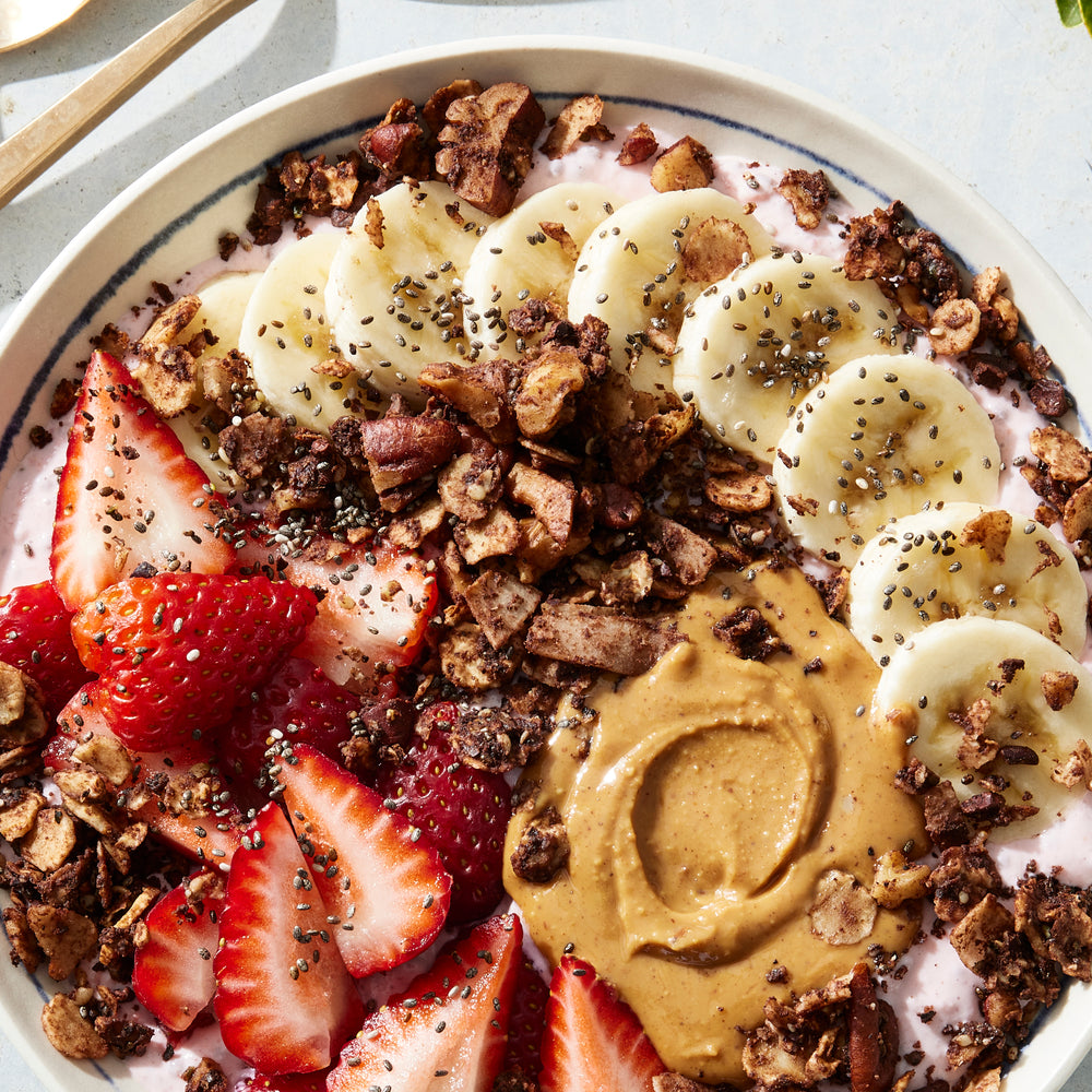 A colorful yogurt bowl topped with strawberries, bananas, nut butter and Struesli's flavorful cacao + coffee granola.
