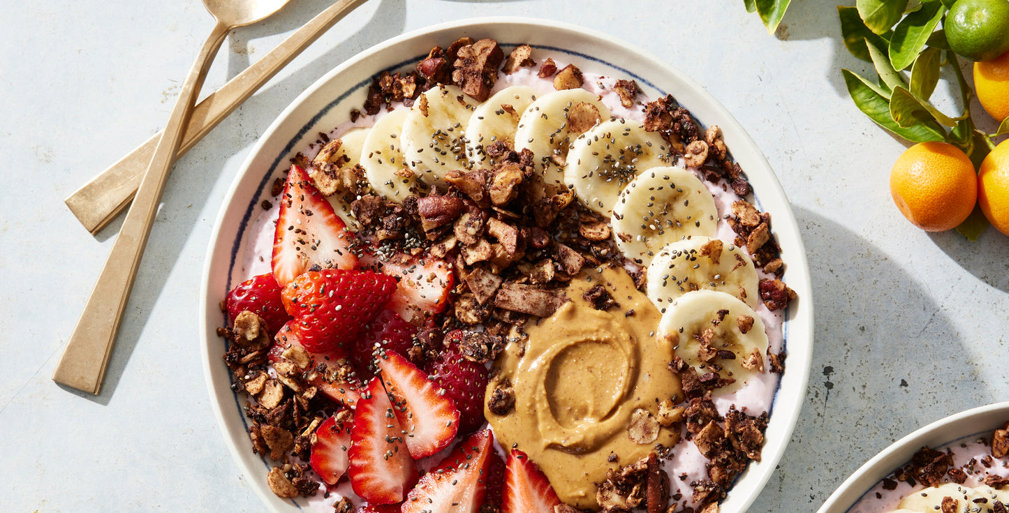 A colorful yogurt bowl topped with strawberries, bananas, nut butter and Struesli's flavorful cacao + coffee granola.